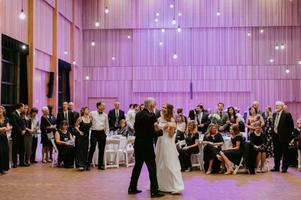 Two people dance in Osberg Great Hall, with purple lighting and white pendants shining above.