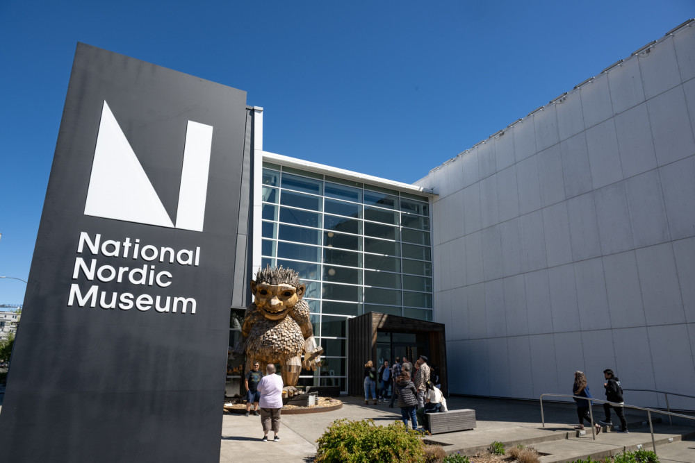 A photo of the National Nordic Museum, with a large sign featuring the Museum logo and a giant wooden troll statue standing outside the entrance.