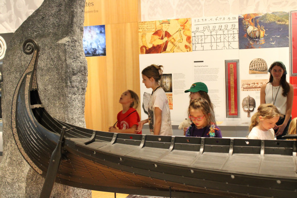 A group of children examines a boat on display in the Nordic Journeys exhibition.
