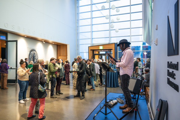 A musician plays the guitar for a group in the sunlit Fjord Hall, near the entrance to the National Nordic Museum.